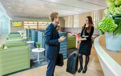 Guest conversing in Munich Airport lounge, Schengen Terminal 1, with modern seating and decor.