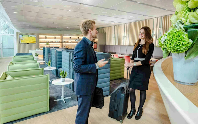 Guest conversing in Munich Airport lounge, Schengen Terminal 1, with modern seating and decor.