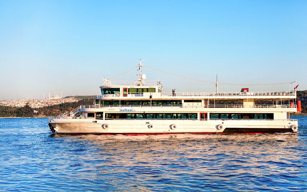Cruise ship on Bosphorus River, Istanbul, with cityscape in background.