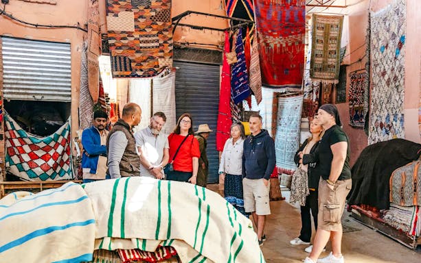 Group exploring vibrant textile market in Marrakech souks.