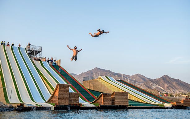 Participants jumping from slides at Hatta Wadi Hub adventure park, UAE.