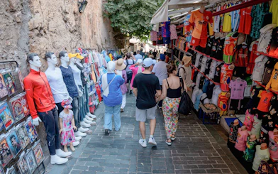 Street market in Antalya with tourists browsing clothing and souvenirs.