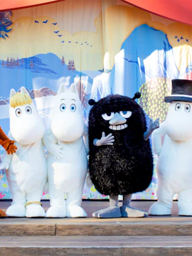 Characters from Moomin Valley Park on stage in front of a colorful backdrop.