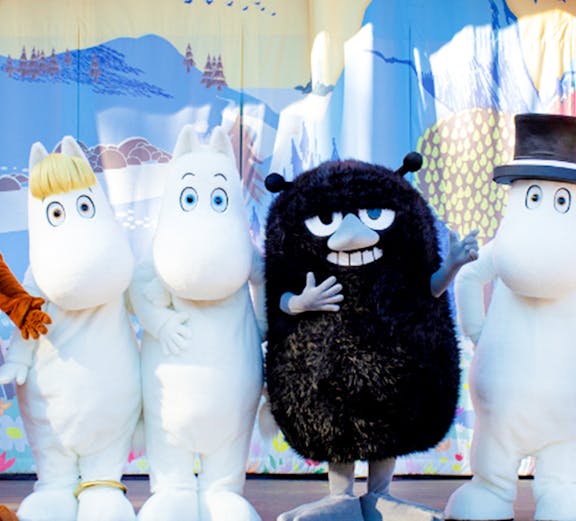 Characters from Moomin Valley Park on stage in front of a colorful backdrop.