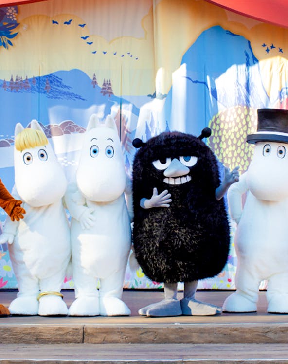 Characters from Moomin Valley Park on stage in front of a colorful backdrop.