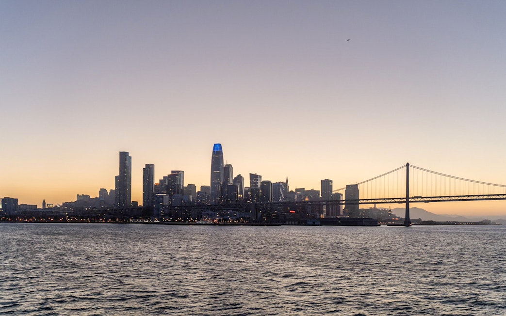 City skyline and bridge at sunset during California cruise.
