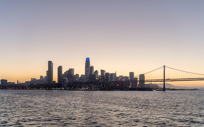 City skyline and bridge at sunset during California cruise.