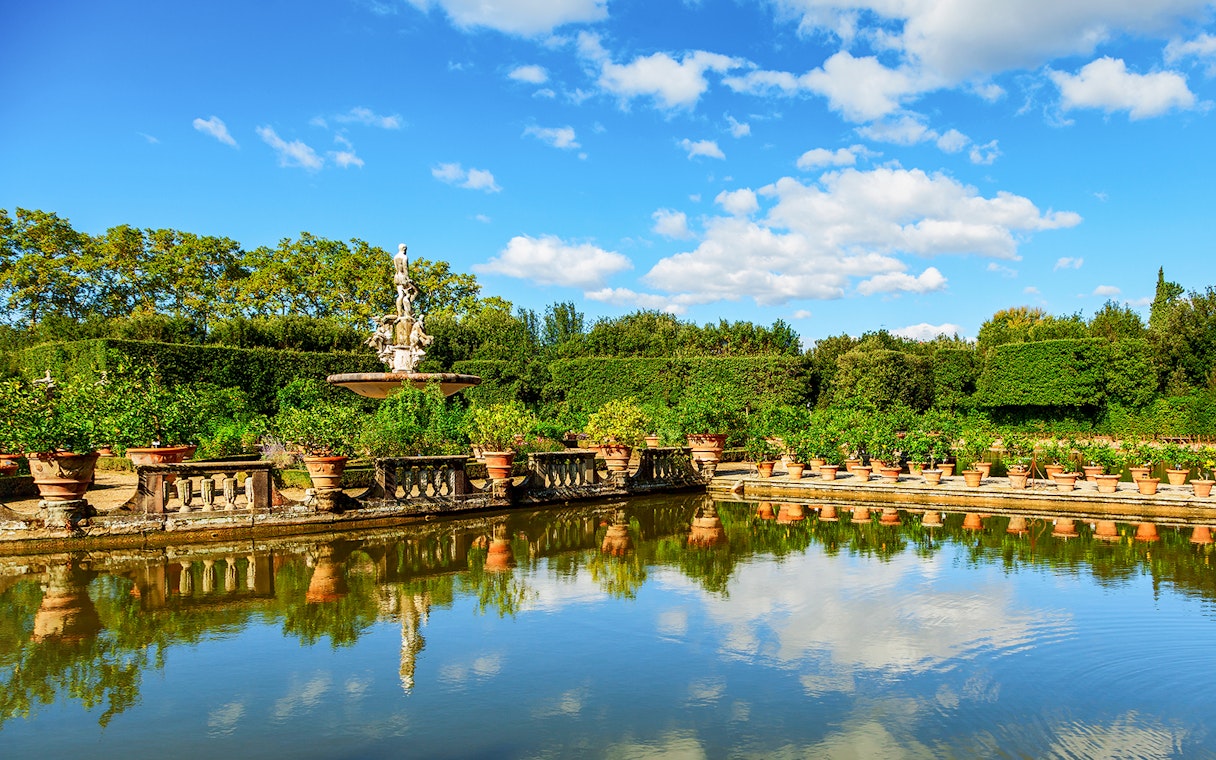 Fountain and greenery at Boboli Gardens, Florence, reflecting in a pond.