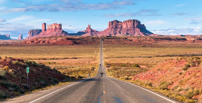 Open road of Route 163 leading to Monument Valley in the background.