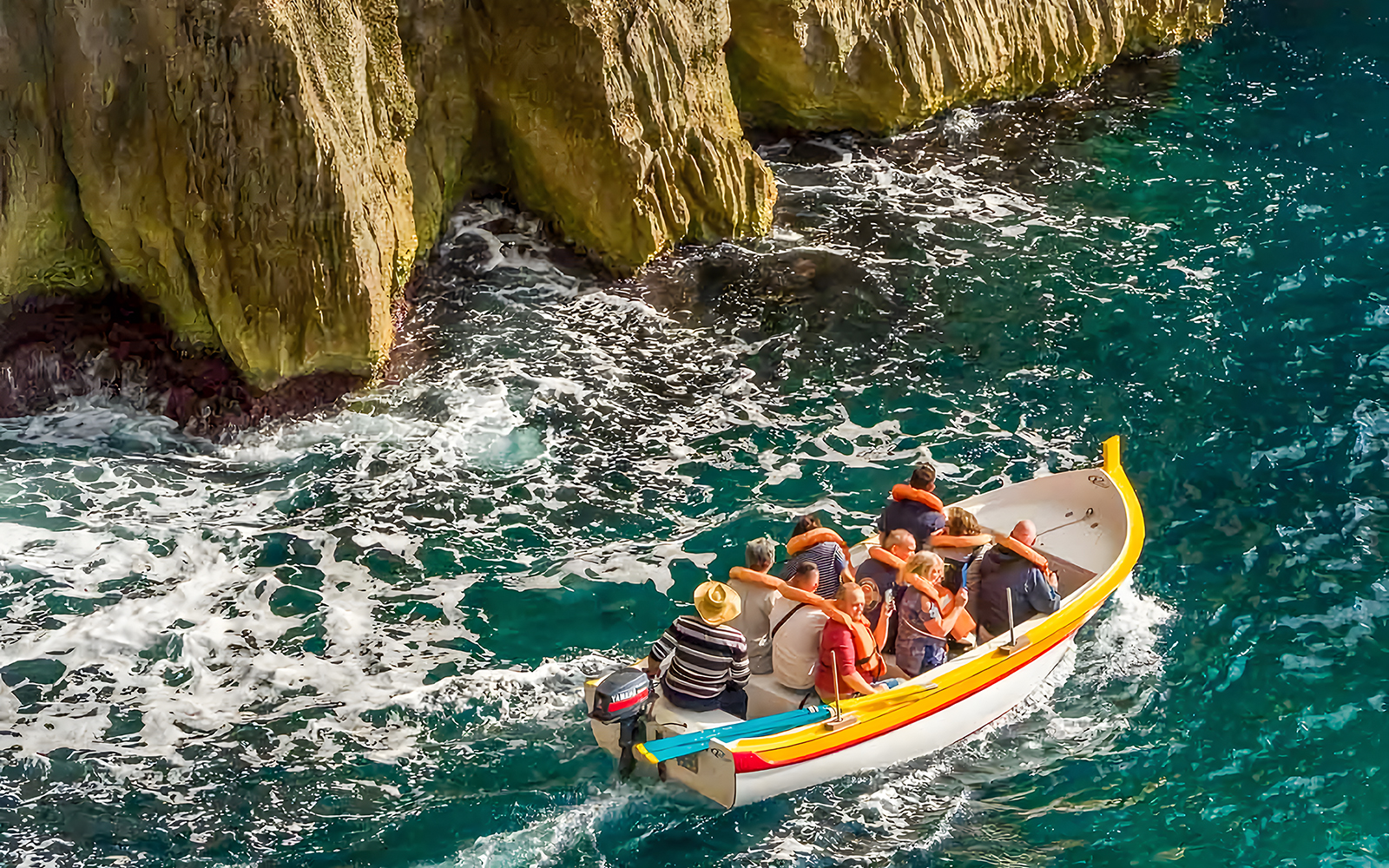 Boat tour near limestone cliffs at Blue Grotto, Malta.