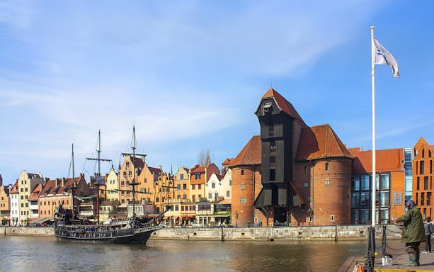 Ship sailing on Motlawa River with historic Gdansk buildings in the background.