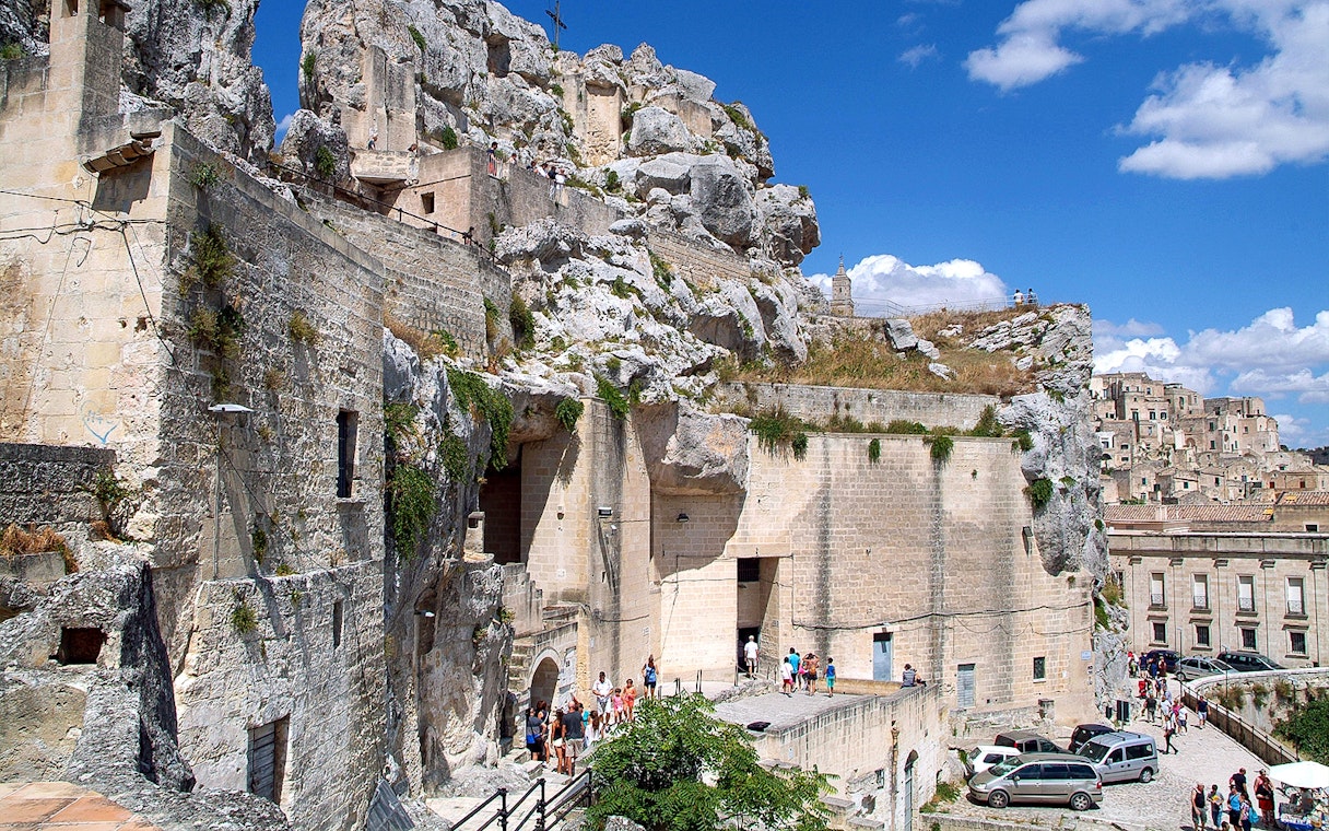 Matera town ancient stone buildings and tourists exploring historic site.