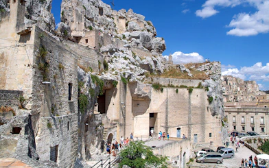 Matera town ancient stone buildings and tourists exploring historic site.