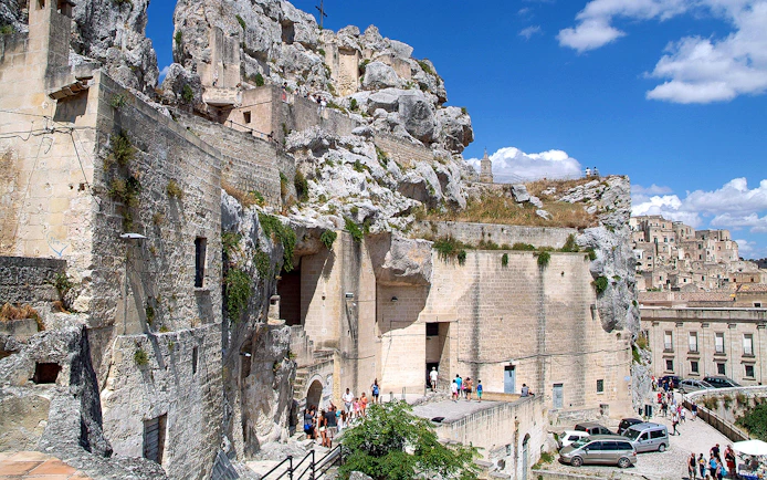 Matera town ancient stone buildings and tourists exploring historic site.