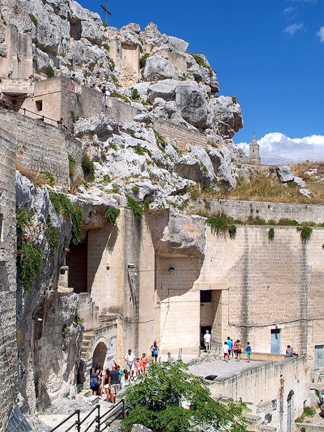 Matera town ancient stone buildings and tourists exploring historic site.