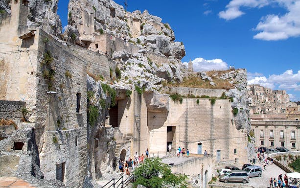 Matera town ancient stone buildings and tourists exploring historic site.