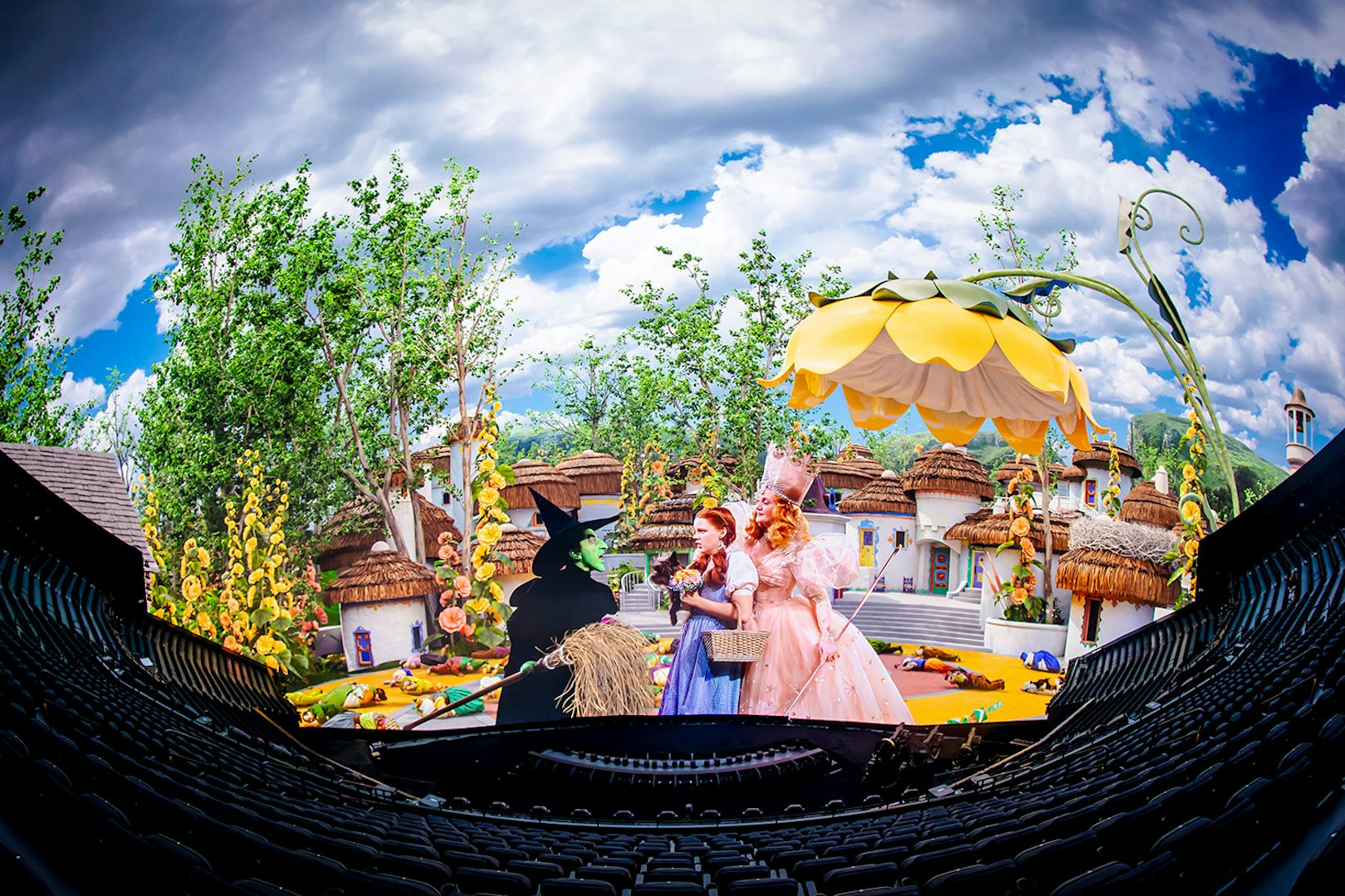 Scene from Wizard of Oz show at Sphere with characters in colorful village setting.