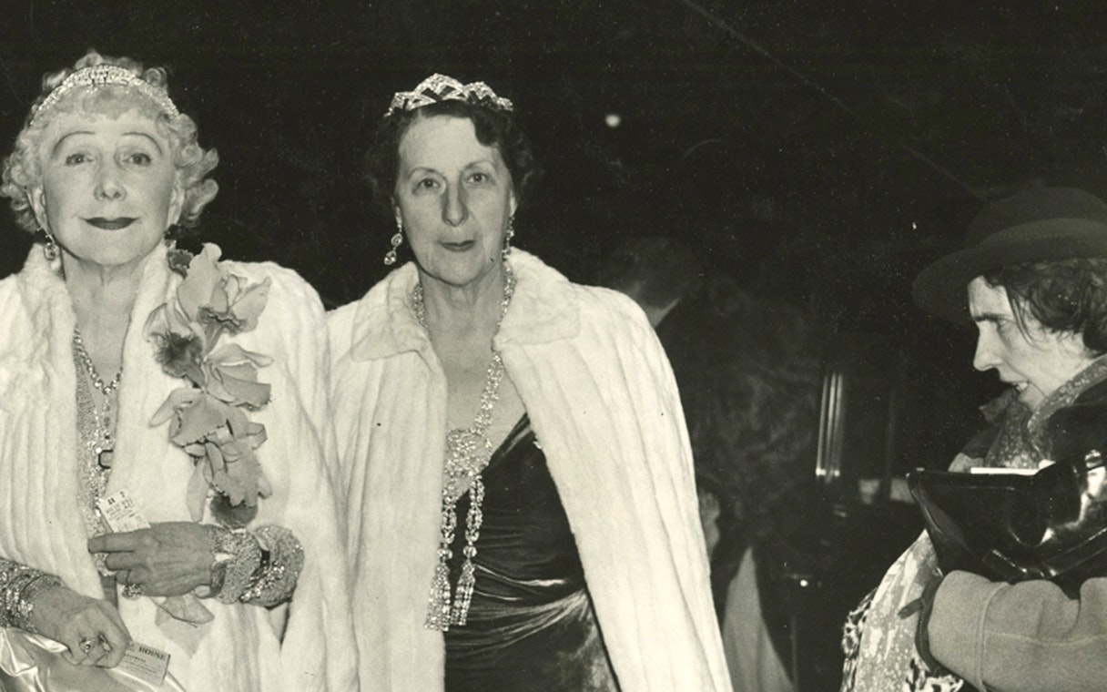 Elegant women in evening attire at an event, holding tickets, related to Recoletos Room at Fundación MAPFRE, Madrid.