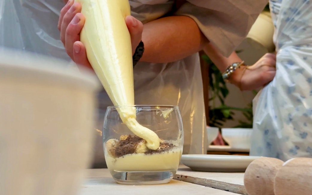 Tiramisu being prepared in a glass during a cooking class in Siena.