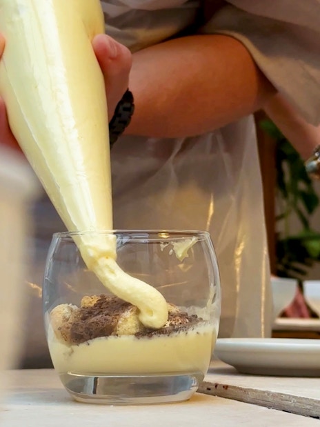 Tiramisu being prepared in a glass during a cooking class in Siena.