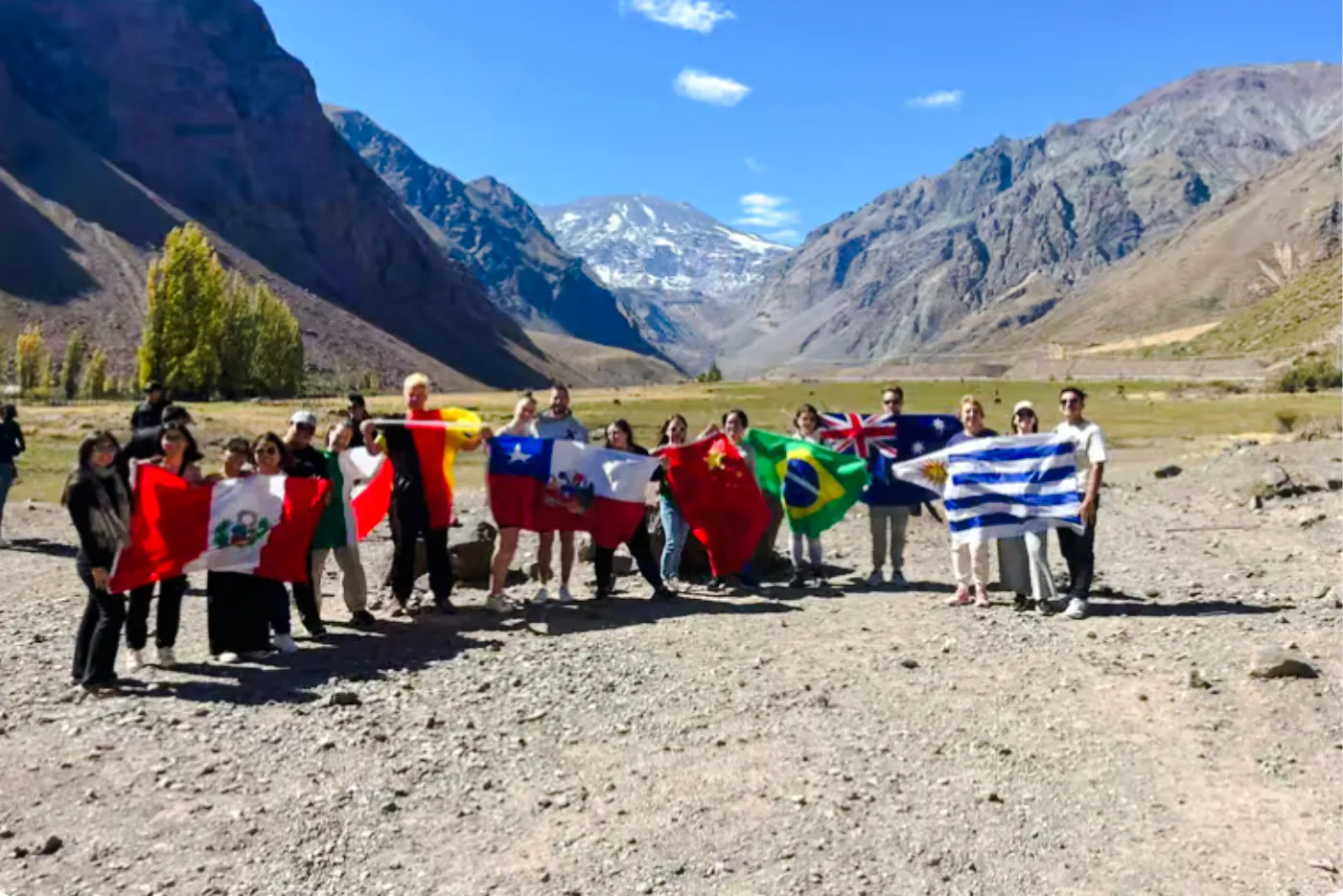 Tourists holding flags at Cajón del Maipo with Andes mountains in the background, Santiago.