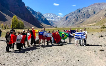 Tourists holding flags at Cajón del Maipo with Andes mountains in the background, Santiago.