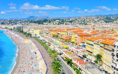 Promenade des Anglais in Nice with beachgoers and colorful buildings along the coastline.