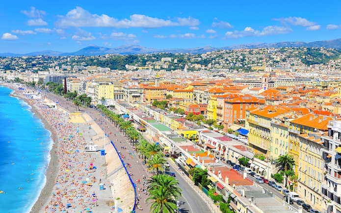 Promenade des Anglais in Nice with beachgoers and colorful buildings along the coastline.