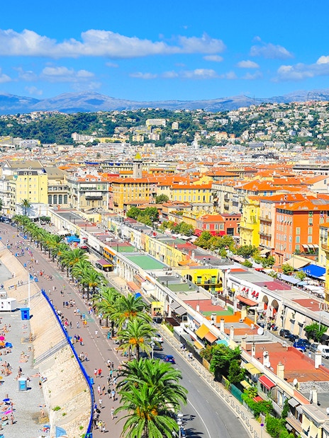 Promenade des Anglais in Nice with beachgoers and colorful buildings along the coastline.