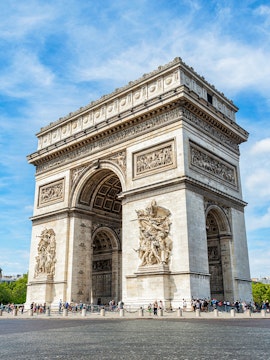 Arc de Triomphe in Paris with detailed sculptures and tourists nearby.