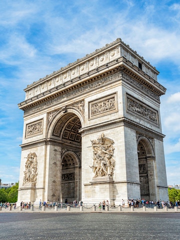 Arc de Triomphe in Paris with detailed sculptures and tourists nearby.