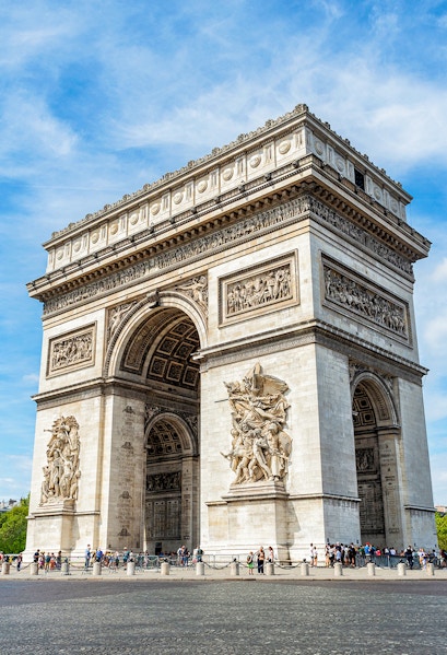 Arc de Triomphe in Paris with detailed sculptures and tourists nearby.