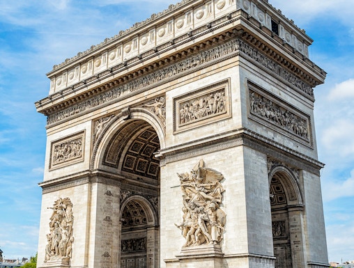 Arc de Triomphe in Paris with detailed sculptures and tourists nearby.