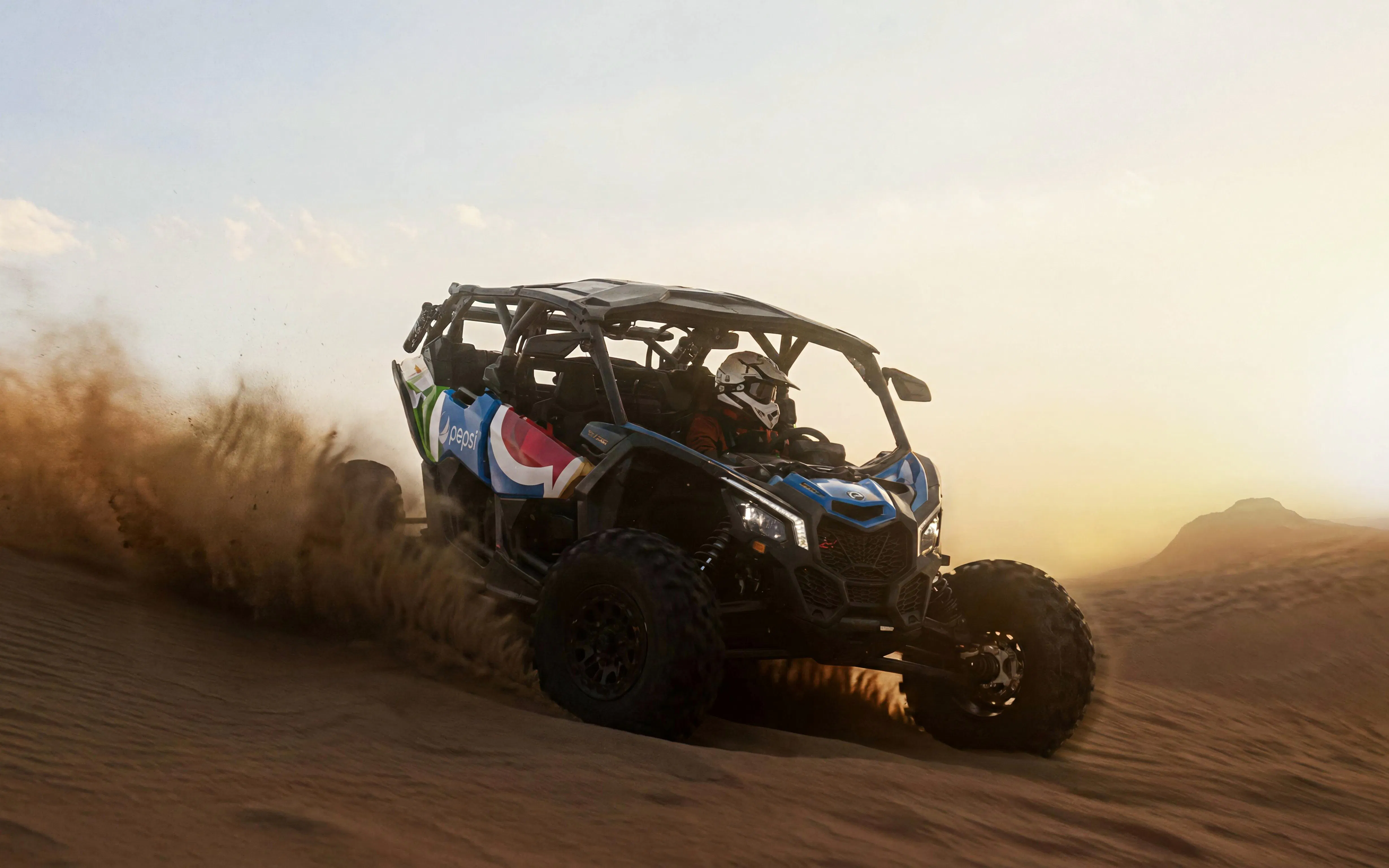 4-seater desert buggy driving through sand dunes at sunset.