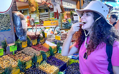 Traveler tasting olives at a vibrant market on Istanbul's Asian side during a walking tour.