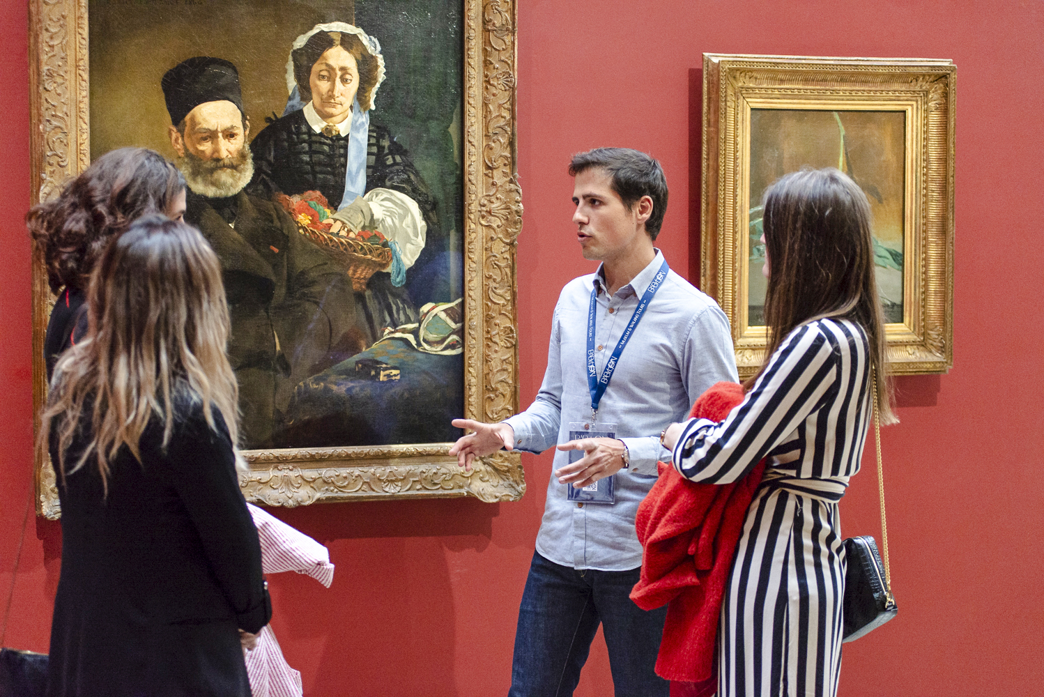 Guide explaining paintings to tourists inside Orsay Museum, France.