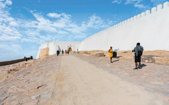 Visitors walking towards the historic walls of Agadir Oufella, Morocco.