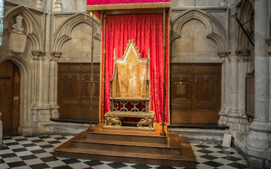 Coronation Chair at Westminster Abbey with red drapery backdrop.