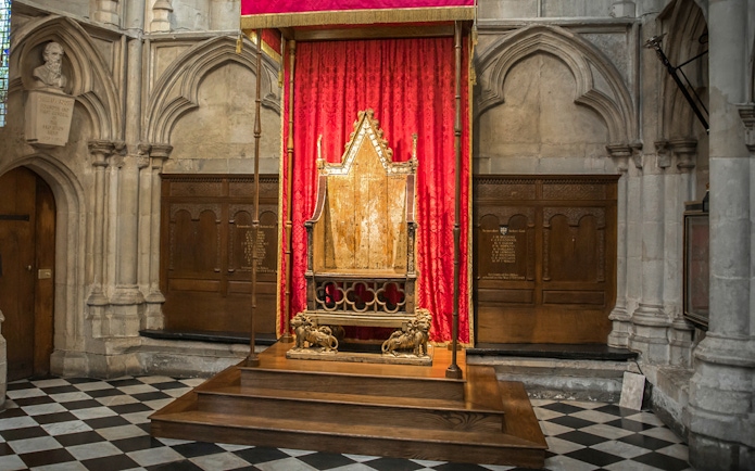 Coronation Chair at Westminster Abbey with red drapery backdrop.