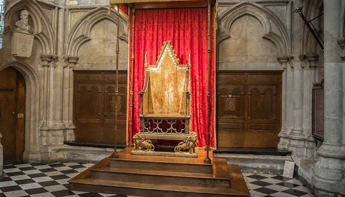 Coronation Chair at Westminster Abbey with red drapery backdrop.
