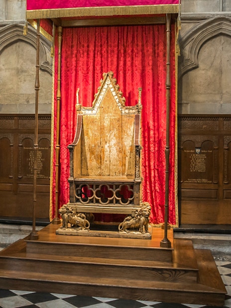 Coronation Chair at Westminster Abbey with red drapery backdrop.