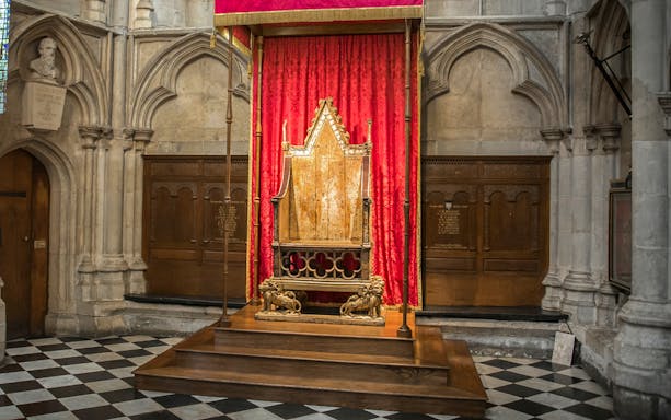 Coronation Chair at Westminster Abbey with red drapery backdrop.