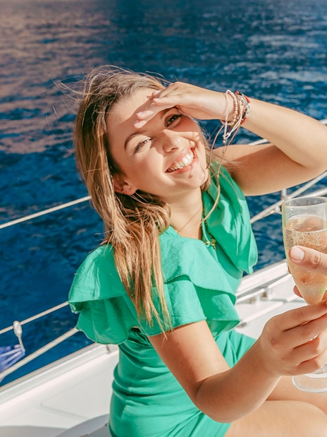 Tourist toasting with champagne on a sailboat during whale and dolphin watching cruise.
