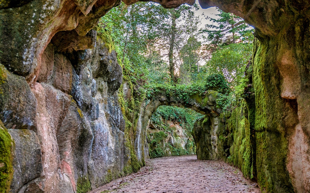 Quinta da Regaleira garden pathway with stone arch and lush greenery.