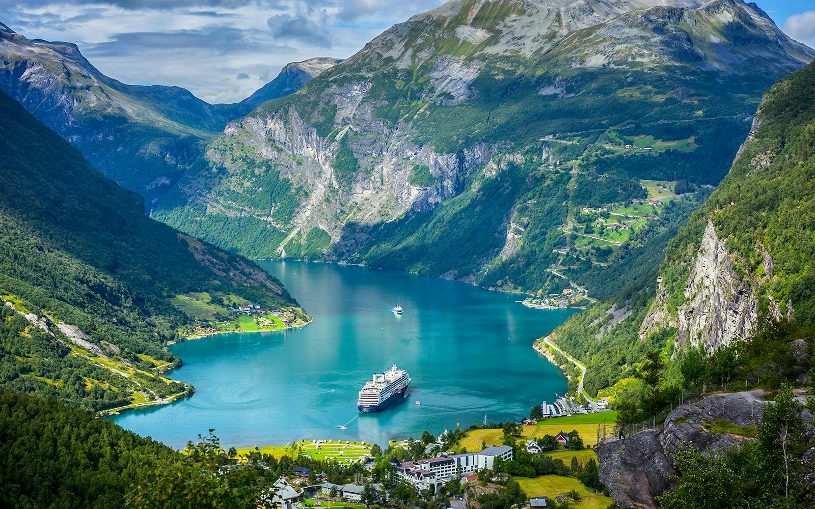 Cruise ship in Geirangerfjord surrounded by mountains on Ålesund-Geiranger-Ålesund tour.