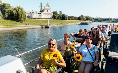 Tourists enjoying a river sightseeing cruise in Krakow with a view of a historic building.