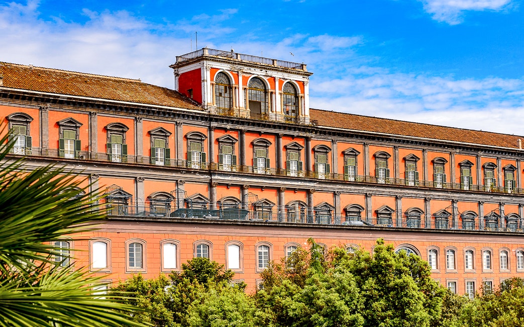 Capodimonte Museum exterior with red facade and arched windows in Naples, Italy.