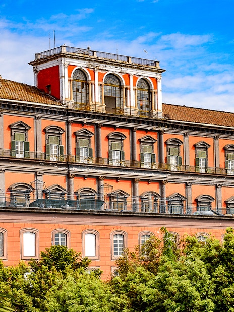 Capodimonte Museum exterior with red facade and arched windows in Naples, Italy.
