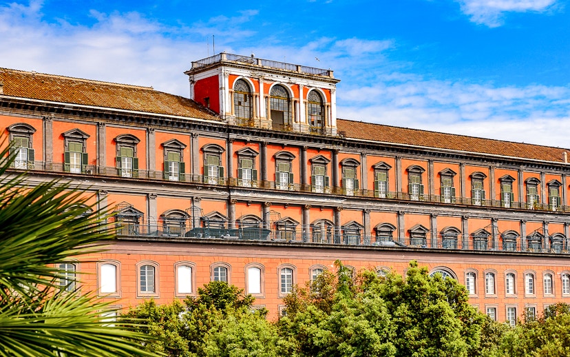 Capodimonte Museum exterior with red facade and arched windows in Naples, Italy.