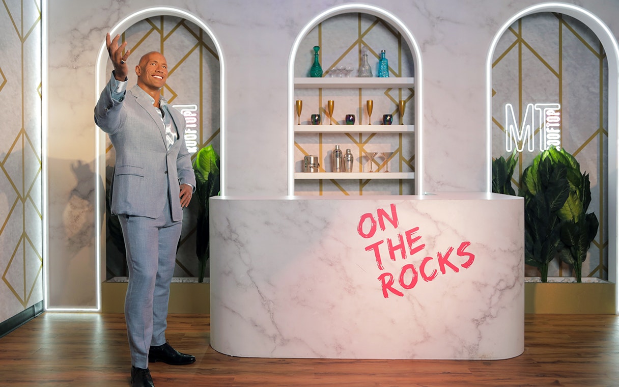 Dwayne Johnson wax statue at Madame Tussauds Dubai in a bar setting.